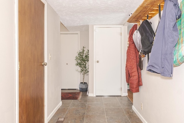 hall with baseboards and a textured ceiling