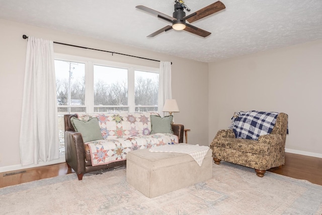 living room featuring baseboards, visible vents, wood finished floors, a textured ceiling, and a ceiling fan