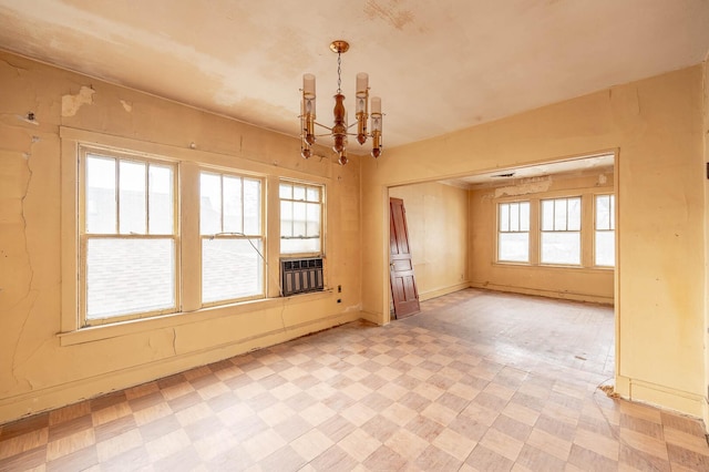 unfurnished room with light floors, cooling unit, baseboards, and a notable chandelier