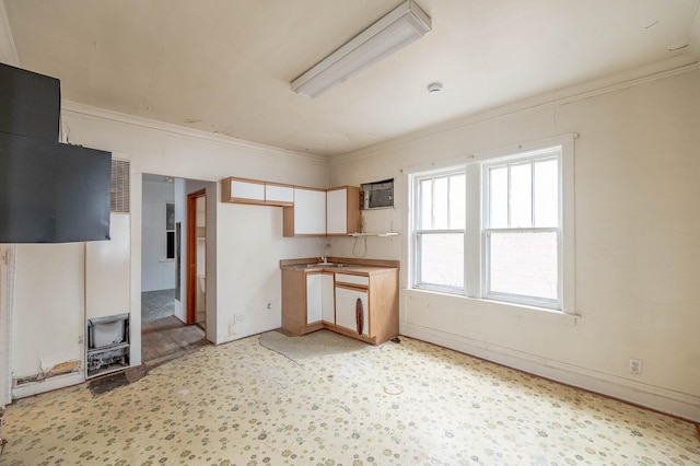 kitchen with ornamental molding, a wood stove, and white cabinets