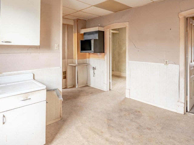 kitchen featuring a wainscoted wall, light countertops, and a drop ceiling