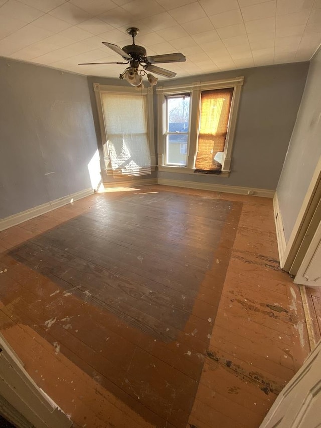 empty room featuring a ceiling fan, baseboards, and wood finished floors