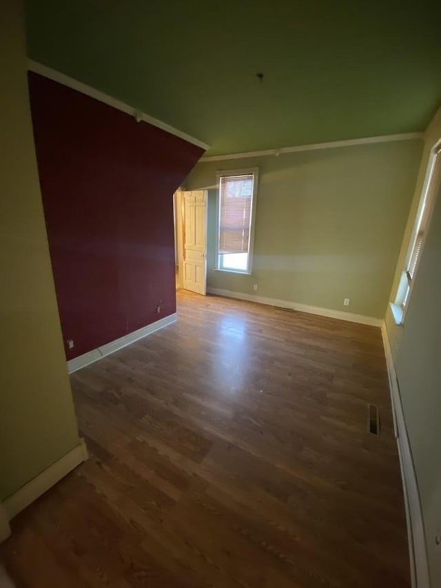 empty room featuring vaulted ceiling, visible vents, dark wood finished floors, and baseboards