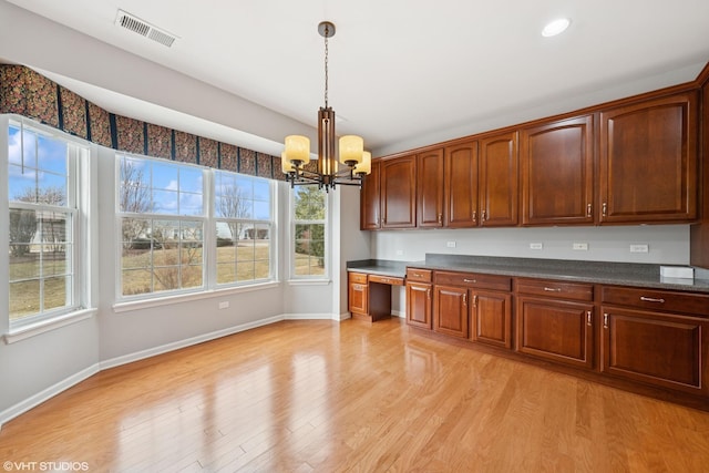 kitchen featuring dark countertops, light wood finished floors, visible vents, and built in study area