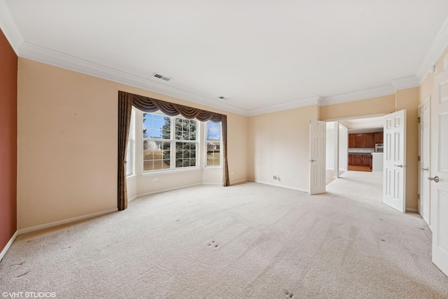 carpeted spare room featuring crown molding, visible vents, and baseboards