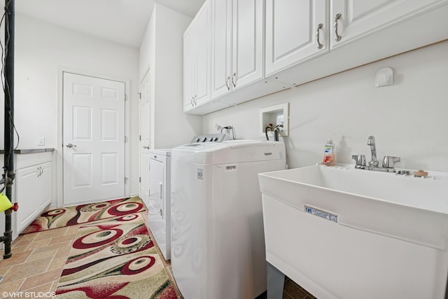 washroom featuring cabinet space, washer and clothes dryer, and a sink