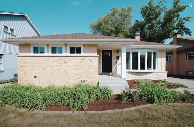 view of front of property featuring board and batten siding, brick siding, and a chimney