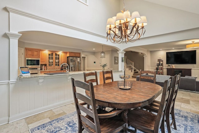 dining area featuring arched walkways, high vaulted ceiling, stone tile flooring, and ornate columns