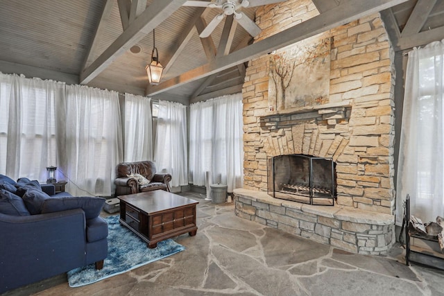 living room with vaulted ceiling with beams, ceiling fan, stone finish floor, and a fireplace