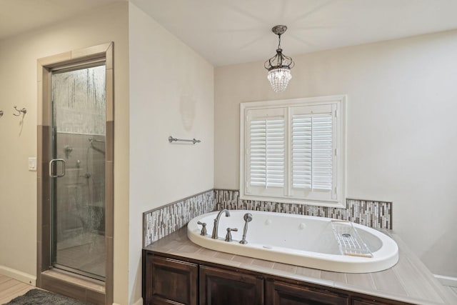 bathroom with a garden tub, a shower stall, and a notable chandelier