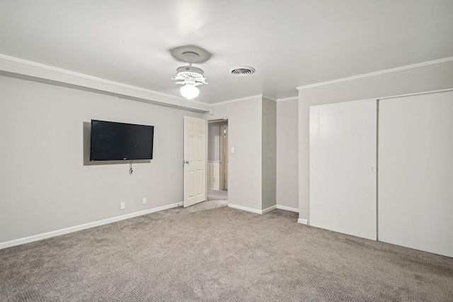 unfurnished bedroom featuring crown molding, a closet, visible vents, carpet flooring, and baseboards