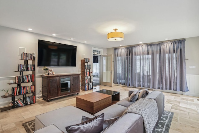 living area with a wainscoted wall, stone tile floors, and recessed lighting