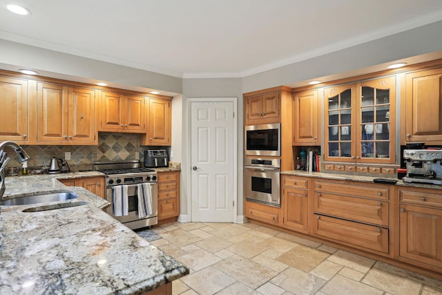 kitchen featuring tasteful backsplash, stone tile floors, light stone counters, stainless steel appliances, and a sink