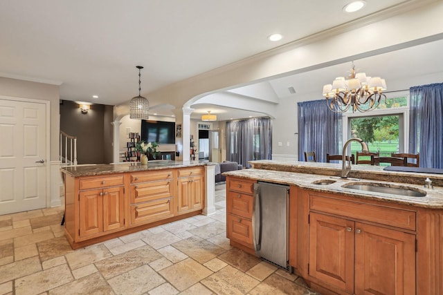 kitchen featuring open floor plan, hanging light fixtures, a sink, and stone tile floors