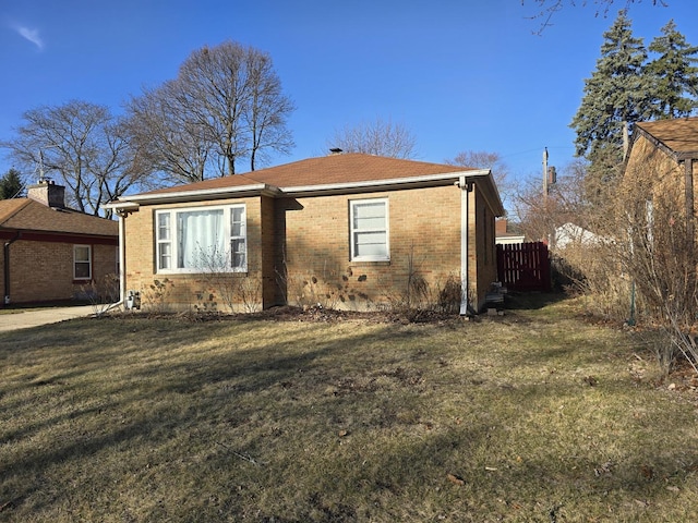 view of front of home featuring a front lawn, fence, and brick siding