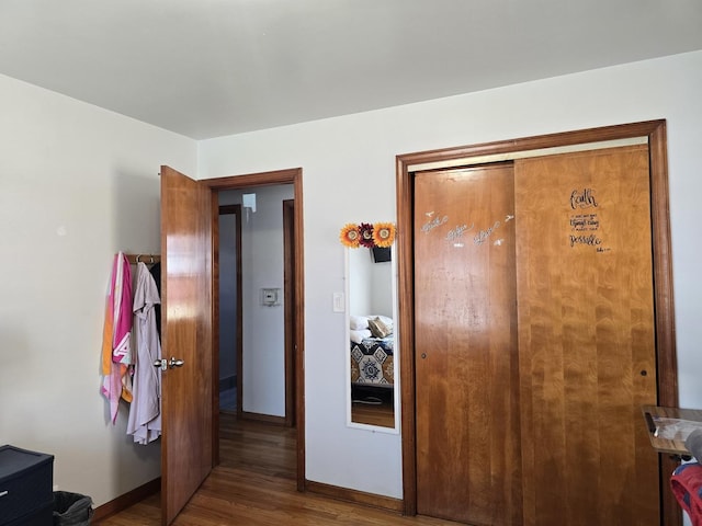 bedroom with a closet, baseboards, and wood finished floors