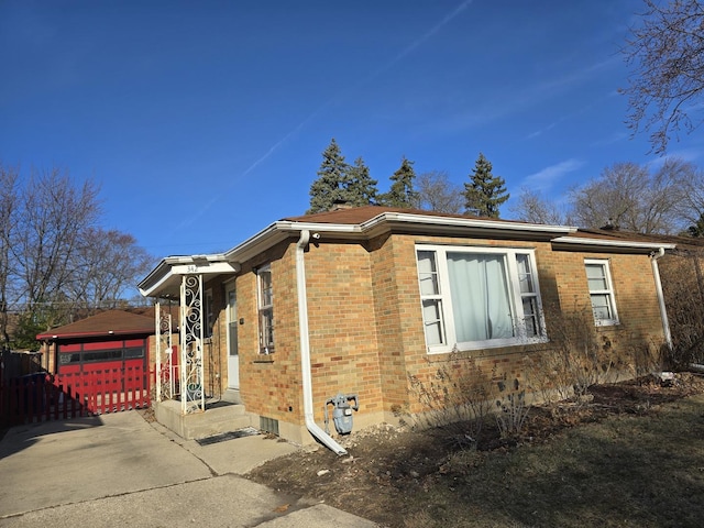 view of side of property featuring concrete driveway, fence, and brick siding