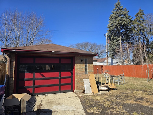 detached garage featuring fence and driveway