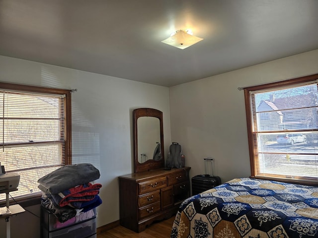 bedroom with dark wood-style floors and multiple windows