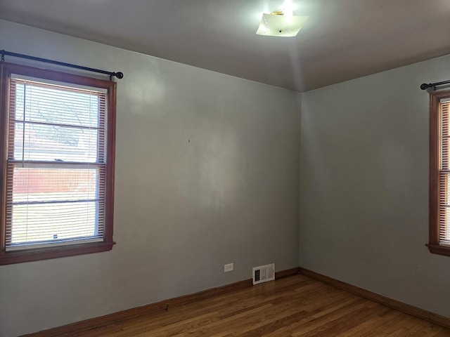 empty room with visible vents, baseboards, and wood finished floors