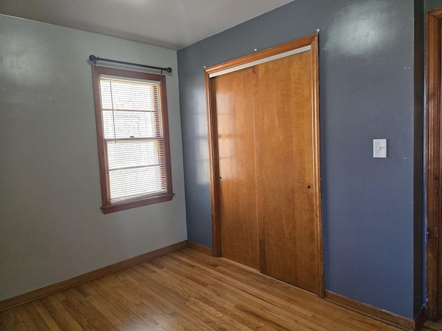 unfurnished bedroom with a closet, baseboards, and wood finished floors