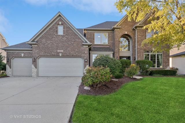 traditional-style home featuring driveway, brick siding, roof with shingles, and a front yard