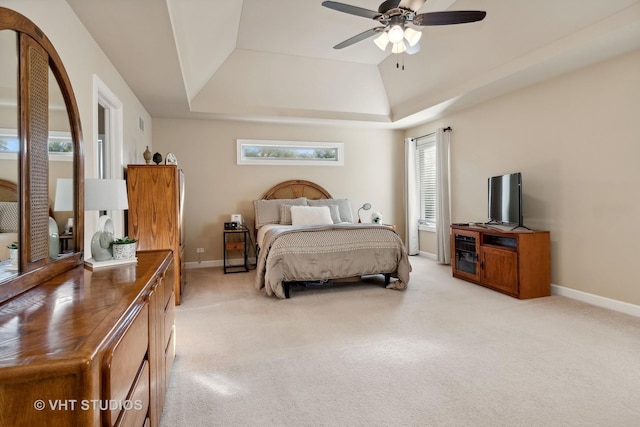 bedroom with light carpet, a raised ceiling, a ceiling fan, and baseboards