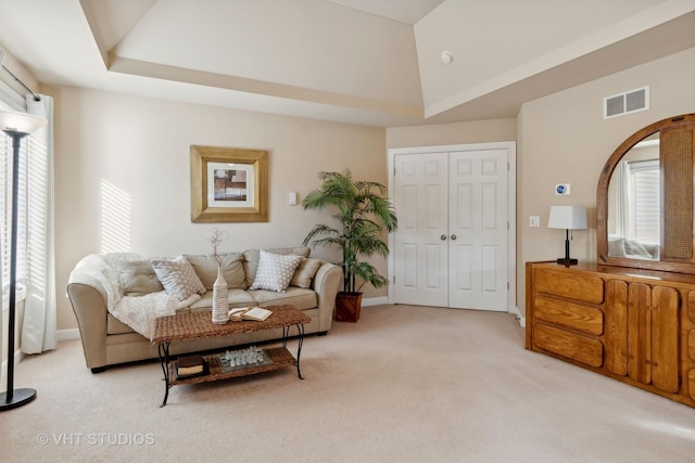 living room with a healthy amount of sunlight, visible vents, vaulted ceiling, and light carpet