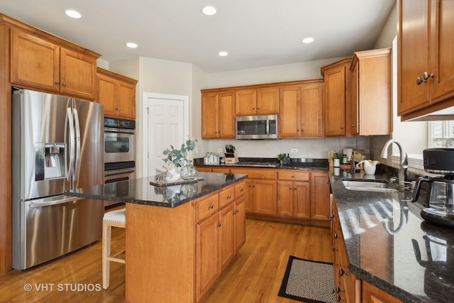 kitchen with brown cabinets, stainless steel appliances, a sink, and a center island