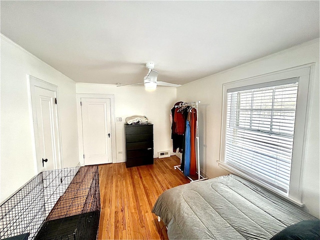 bedroom with ceiling fan, visible vents, and wood finished floors