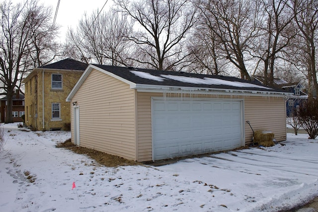 snow covered garage featuring a detached garage