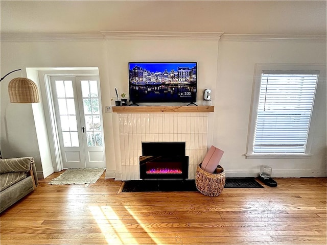 living room featuring a fireplace with flush hearth, ornamental molding, wood finished floors, and baseboards