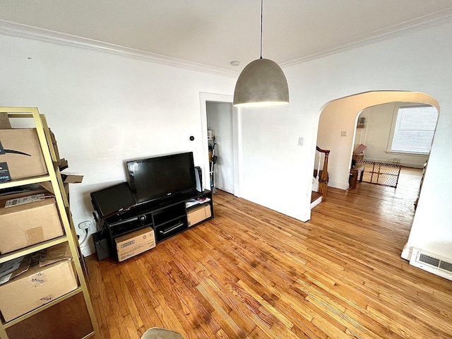 living area featuring arched walkways, crown molding, stairway, and wood finished floors