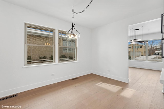 unfurnished dining area with light wood-style floors, baseboards, and visible vents