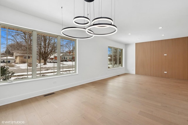 unfurnished dining area with light wood-type flooring, plenty of natural light, visible vents, and baseboards