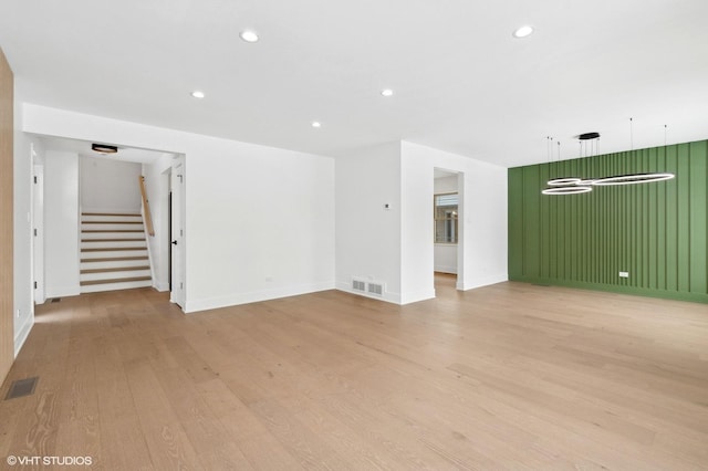 unfurnished living room with light wood-style floors, recessed lighting, visible vents, and stairway