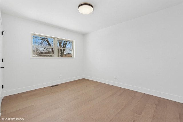 spare room with baseboards, visible vents, and light wood-style floors