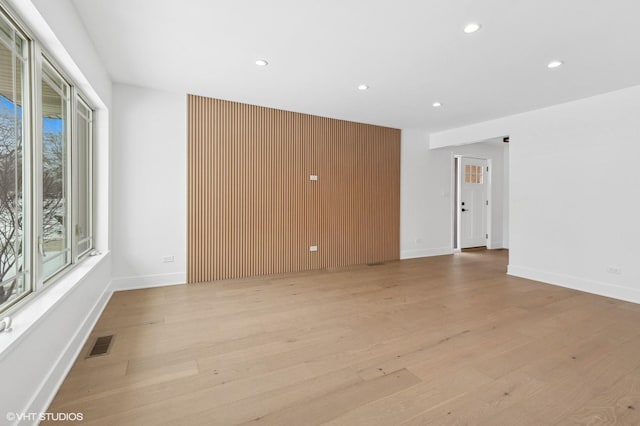 empty room with light wood-style flooring, visible vents, baseboards, and recessed lighting