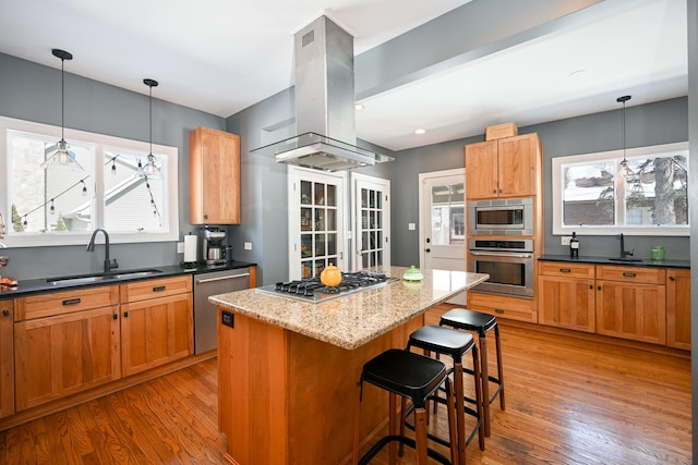 kitchen featuring island range hood, a breakfast bar, a center island, stainless steel appliances, and a sink