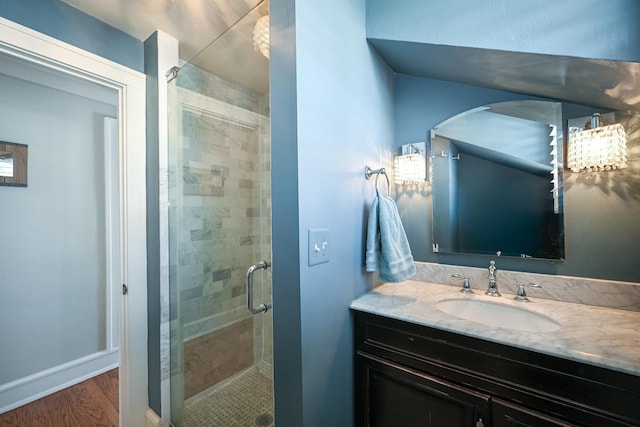 bathroom with a stall shower, vanity, baseboards, and wood finished floors