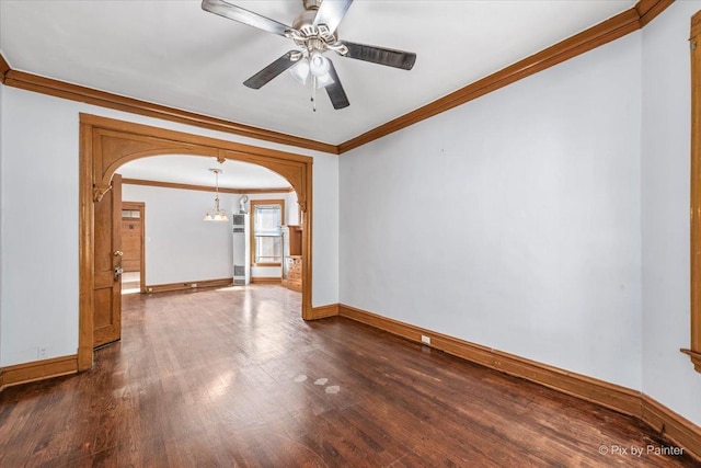 empty room featuring arched walkways, dark wood finished floors, a ceiling fan, and baseboards