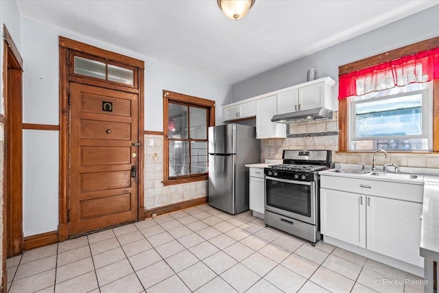 kitchen with light countertops, appliances with stainless steel finishes, white cabinetry, a sink, and under cabinet range hood