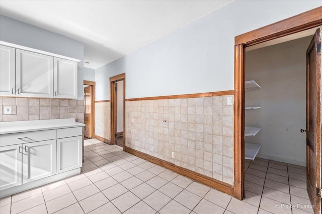 interior space with light tile patterned floors, tile walls, white cabinets, and light countertops