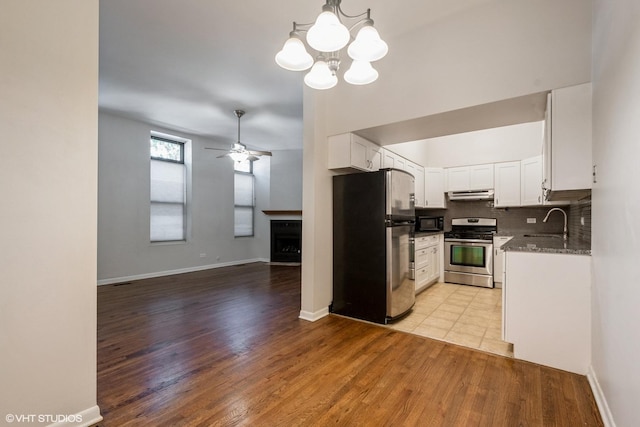 kitchen featuring appliances with stainless steel finishes, open floor plan, hanging light fixtures, white cabinetry, and a sink