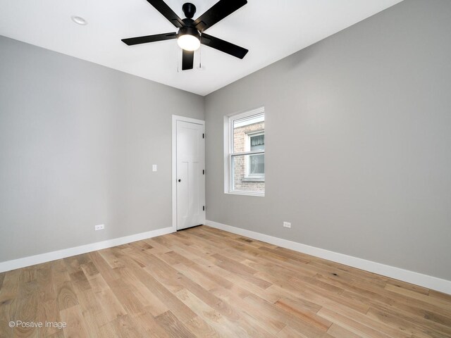 spare room featuring light wood finished floors, ceiling fan, and baseboards