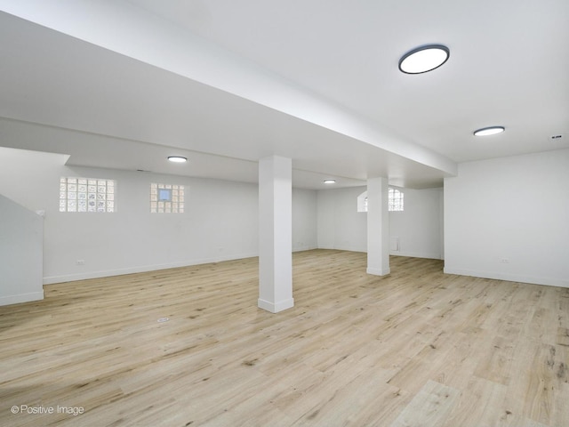 below grade area with a wealth of natural light, baseboards, and wood finished floors