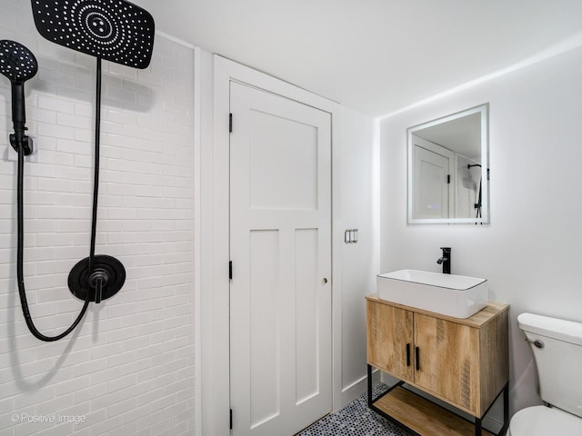 full bathroom with toilet, a tile shower, and vanity