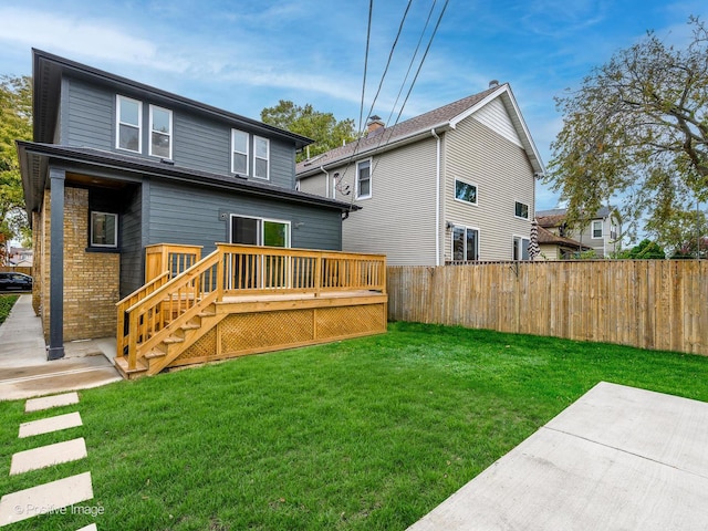 rear view of house featuring a lawn, fence, a wooden deck, a patio area, and brick siding