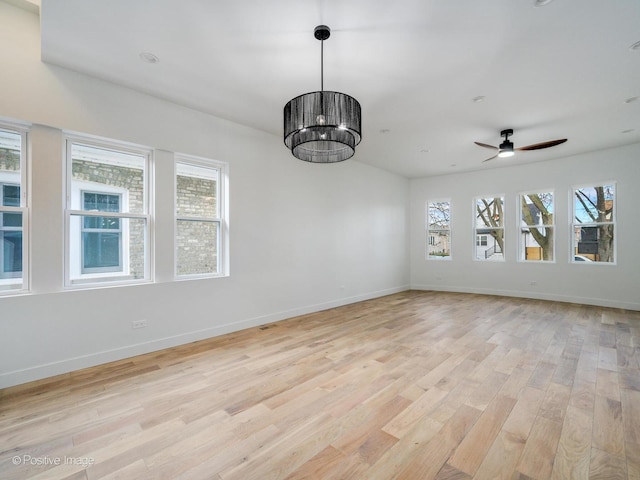 spare room with baseboards, ceiling fan, light wood-style floors, and a healthy amount of sunlight