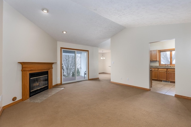 unfurnished living room featuring light carpet, a sink, a fireplace with flush hearth, baseboards, and vaulted ceiling